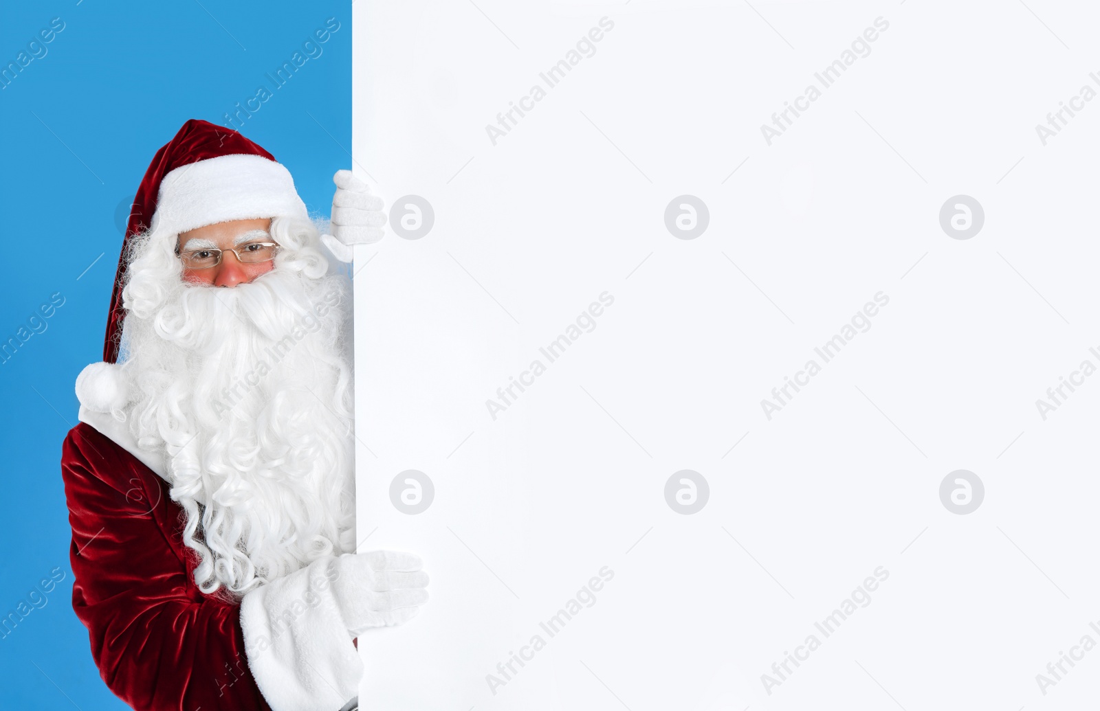 Photo of Santa Claus holding empty banner on light blue background