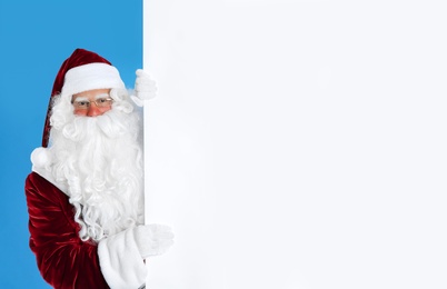 Photo of Santa Claus holding empty banner on light blue background