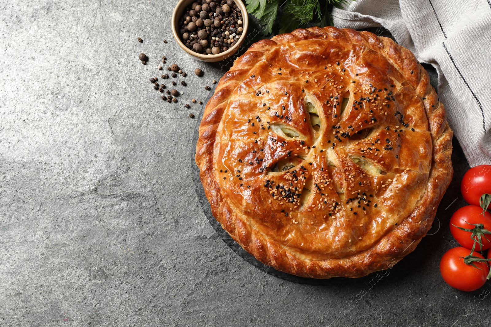 Photo of Tasty homemade pie, spices and fresh tomatoes on grey table, flat lay. Space for text