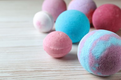 Photo of Colorful bath bombs on white wooden table, space for text