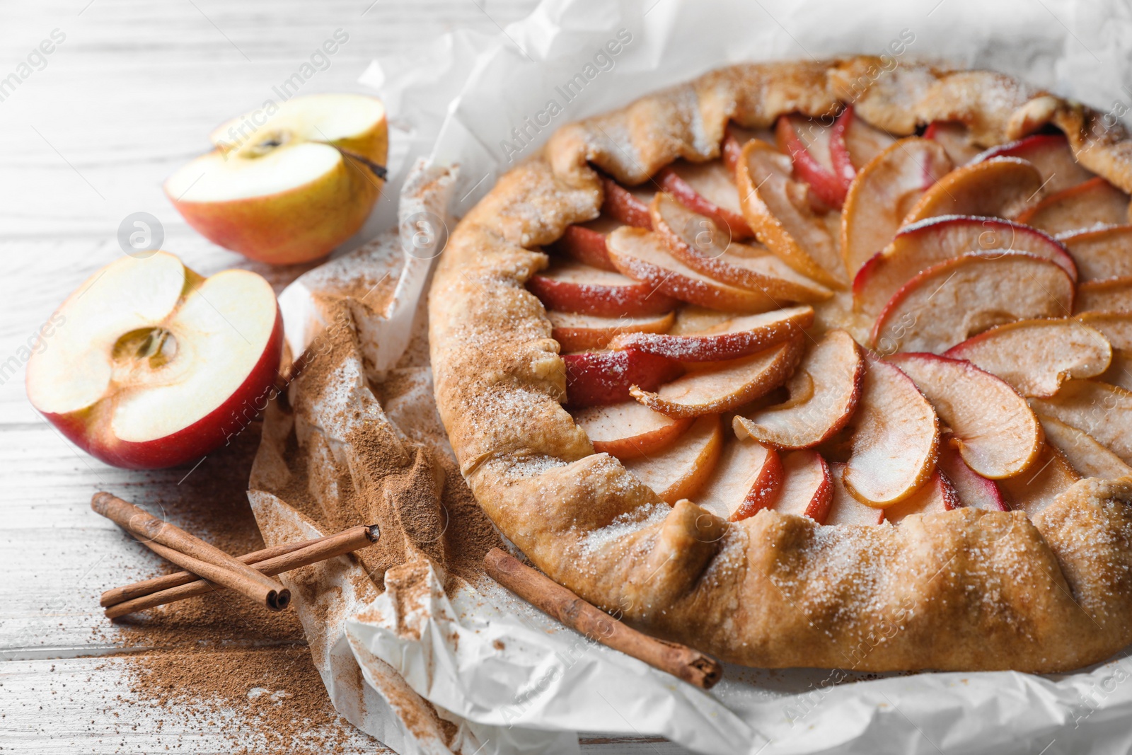 Photo of Delicious apple galette and cinnamon on wooden table