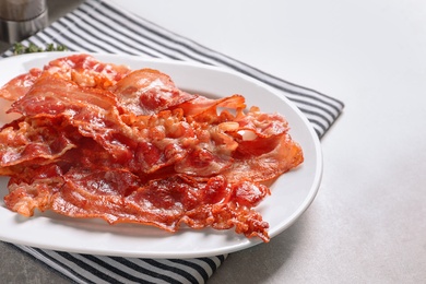 Plate with fried bacon on table