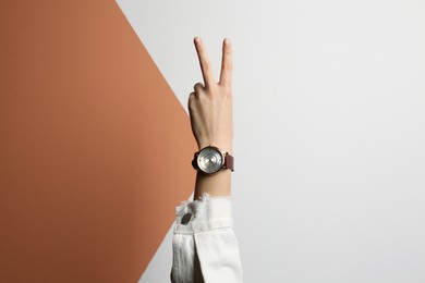 Woman wearing luxury wristwatch on color background, closeup