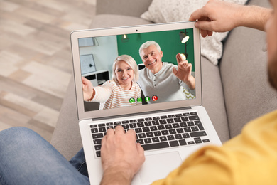 Young man having video chat with his grandparents at home, focus on screen