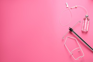 IV infusion set on pink background, flat lay. Space for text