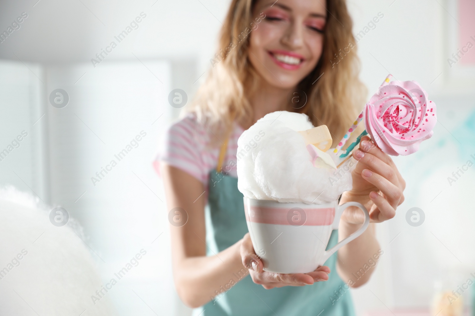 Photo of Young woman with cup of cotton candy dessert indoors, closeup. Space for text