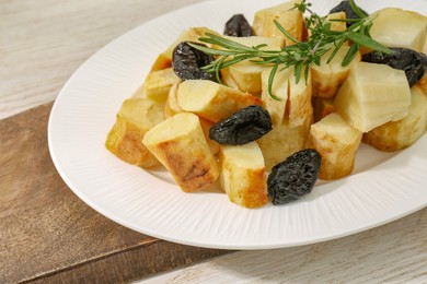 Tasty homemade parsnips with prunes and rosemary on white wooden table, closeup