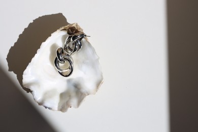 Stylish metal earrings in seashell on white table, top view. Space for text