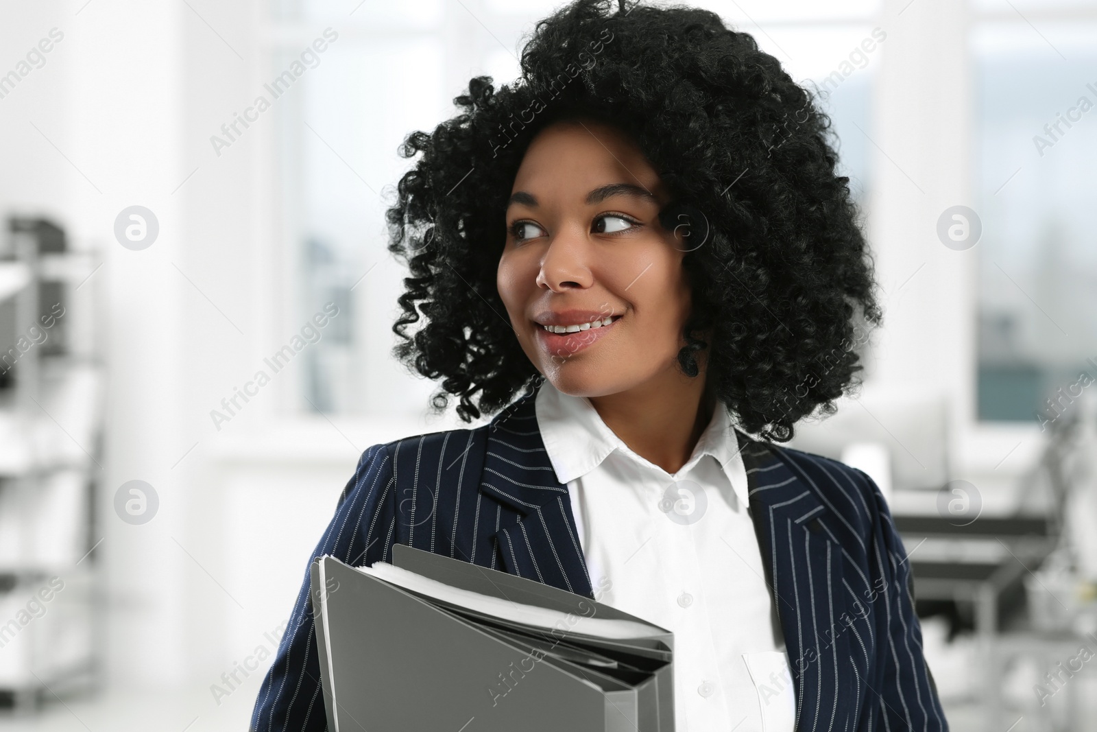 Photo of Smiling young businesswoman with folders in office