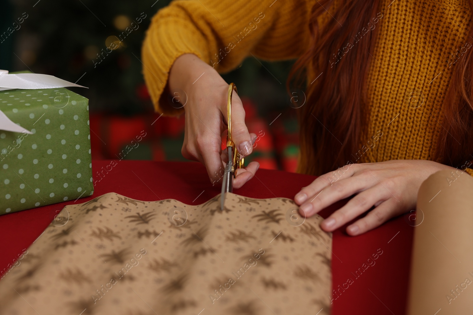 Photo of Woman cutting wrapping paper at table, closeup. Decorating Christmas present