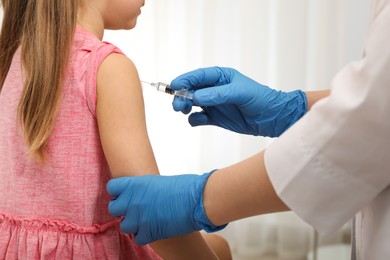 Photo of Doctor giving injection to little girl in hospital, closeup. Immunization concept