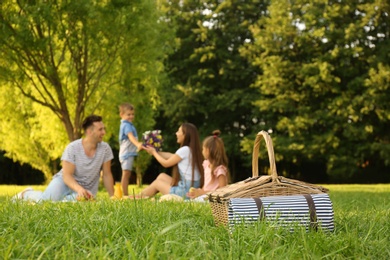 Photo of Picnic basket and happy family on background in park