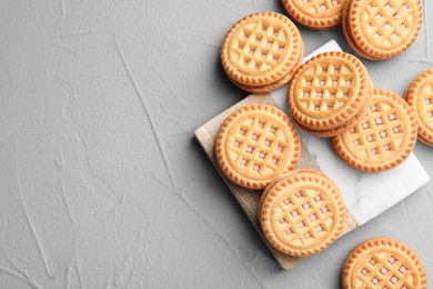 Photo of Tasty sandwich cookies with cream on light grey table, flat lay. Space for text