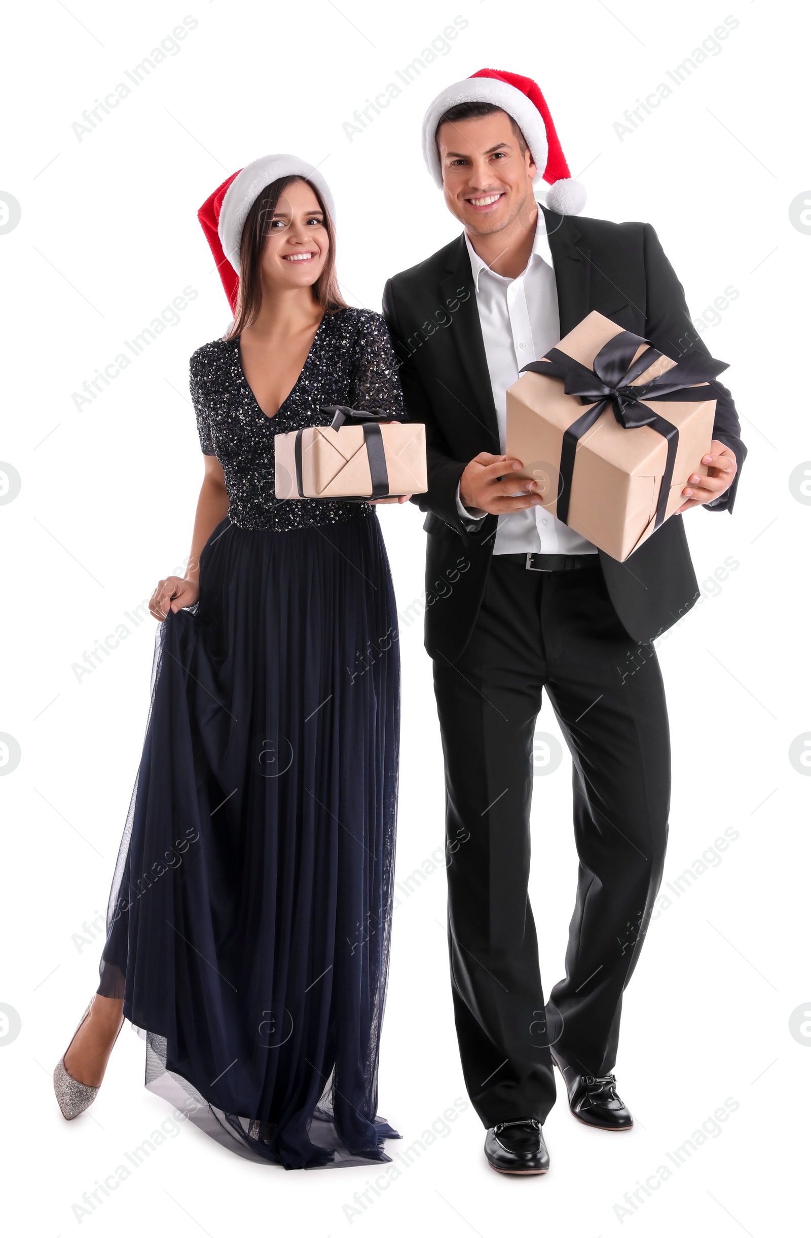 Photo of Beautiful happy couple in Santa hats holding Christmas gifts on white background