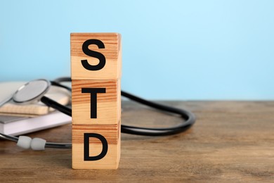 Abbreviation STD made with cubes on wooden table, space for text