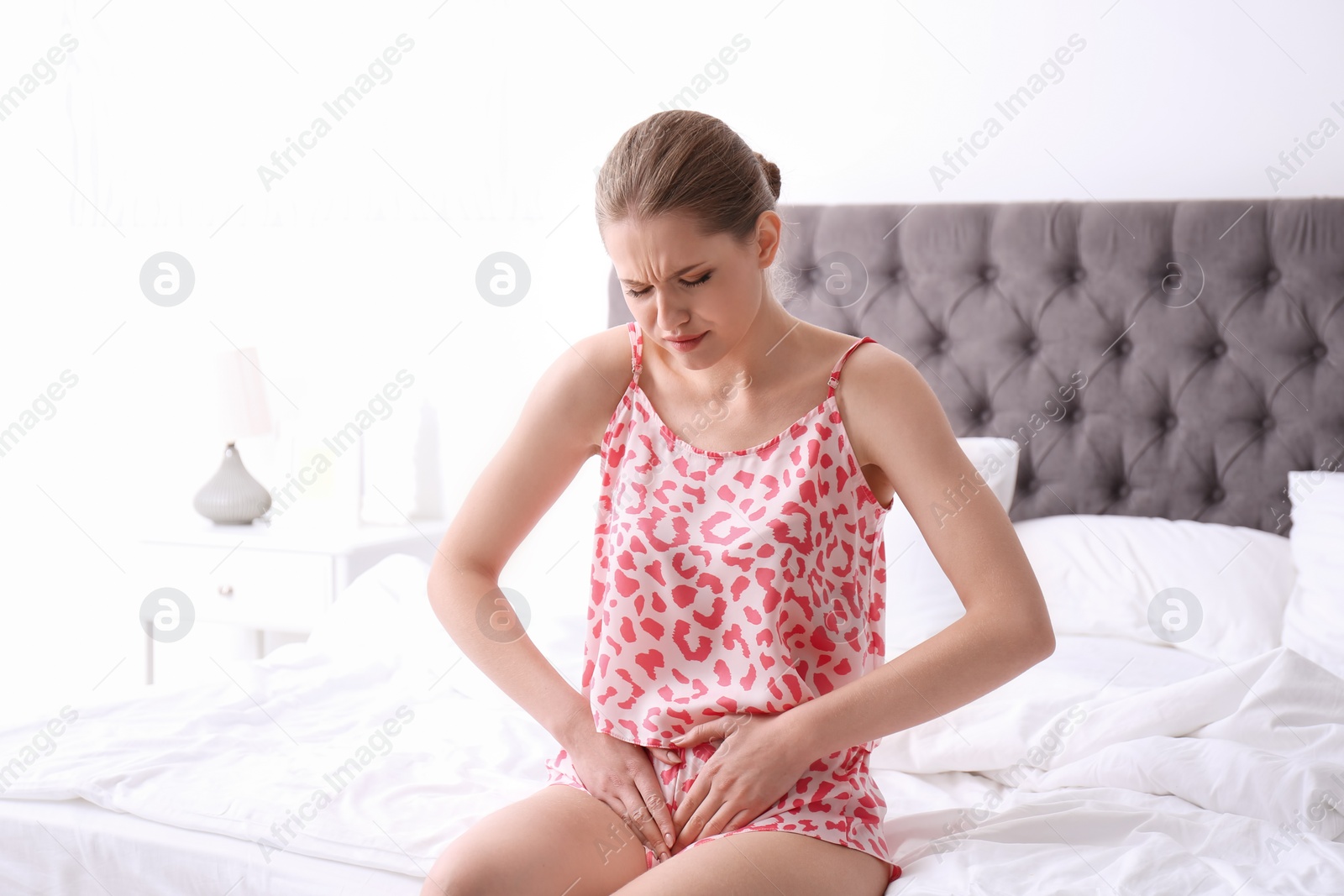 Photo of Young woman suffering from menstrual cramps at home. Gynecology