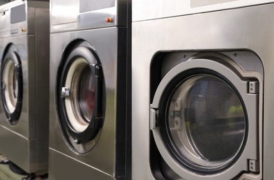Row of modern washing machines in dry-cleaning, closeup