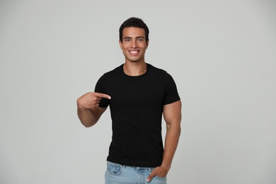 Photo of Handsome young African-American man in blank t-shirt on light background. Space for design