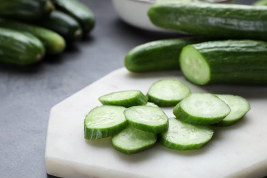Photo of Whole and cut fresh ripe cucumbers on white board, closeup