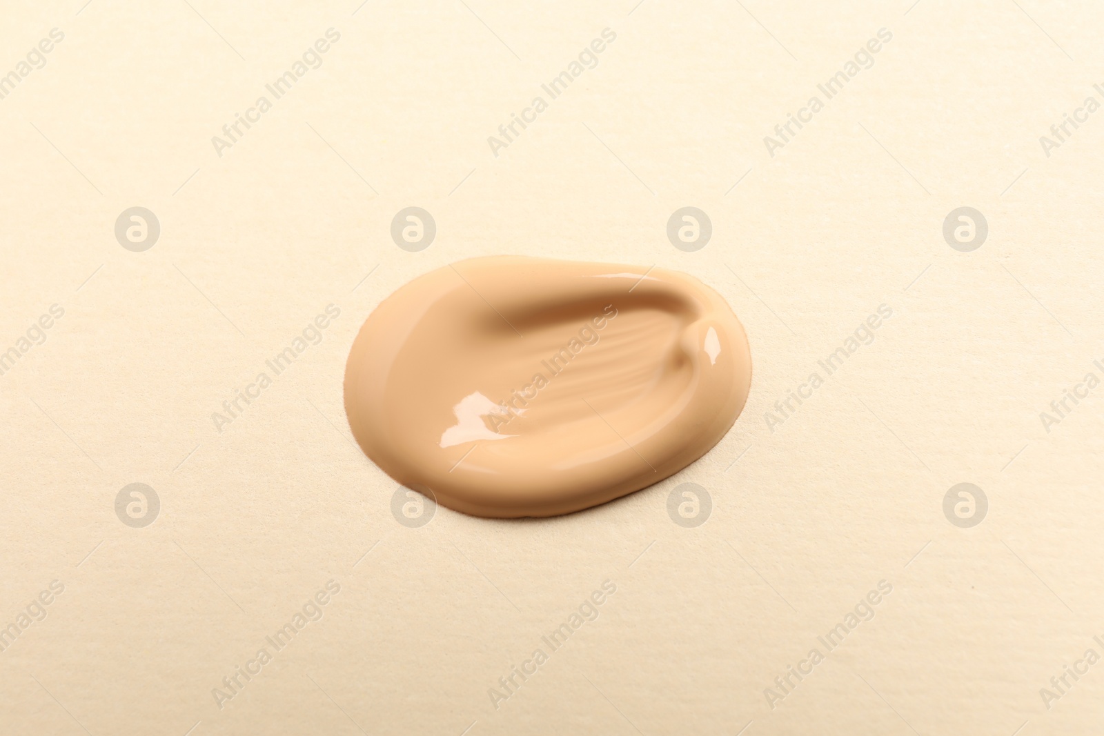 Photo of Sample of skin foundation on beige background, top view