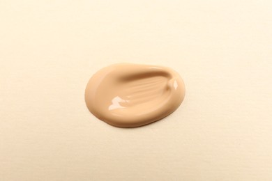 Photo of Sample of skin foundation on beige background, top view