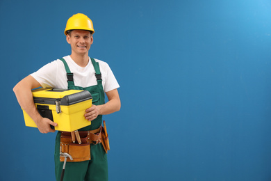 Photo of Handsome carpenter with tool box on blue background. Space for text