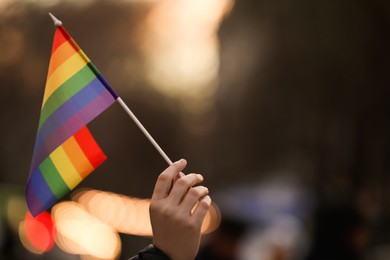 Photo of Woman holding small LGBT flag on city street, closeup. Space for text