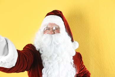 Authentic Santa Claus taking selfie on yellow background