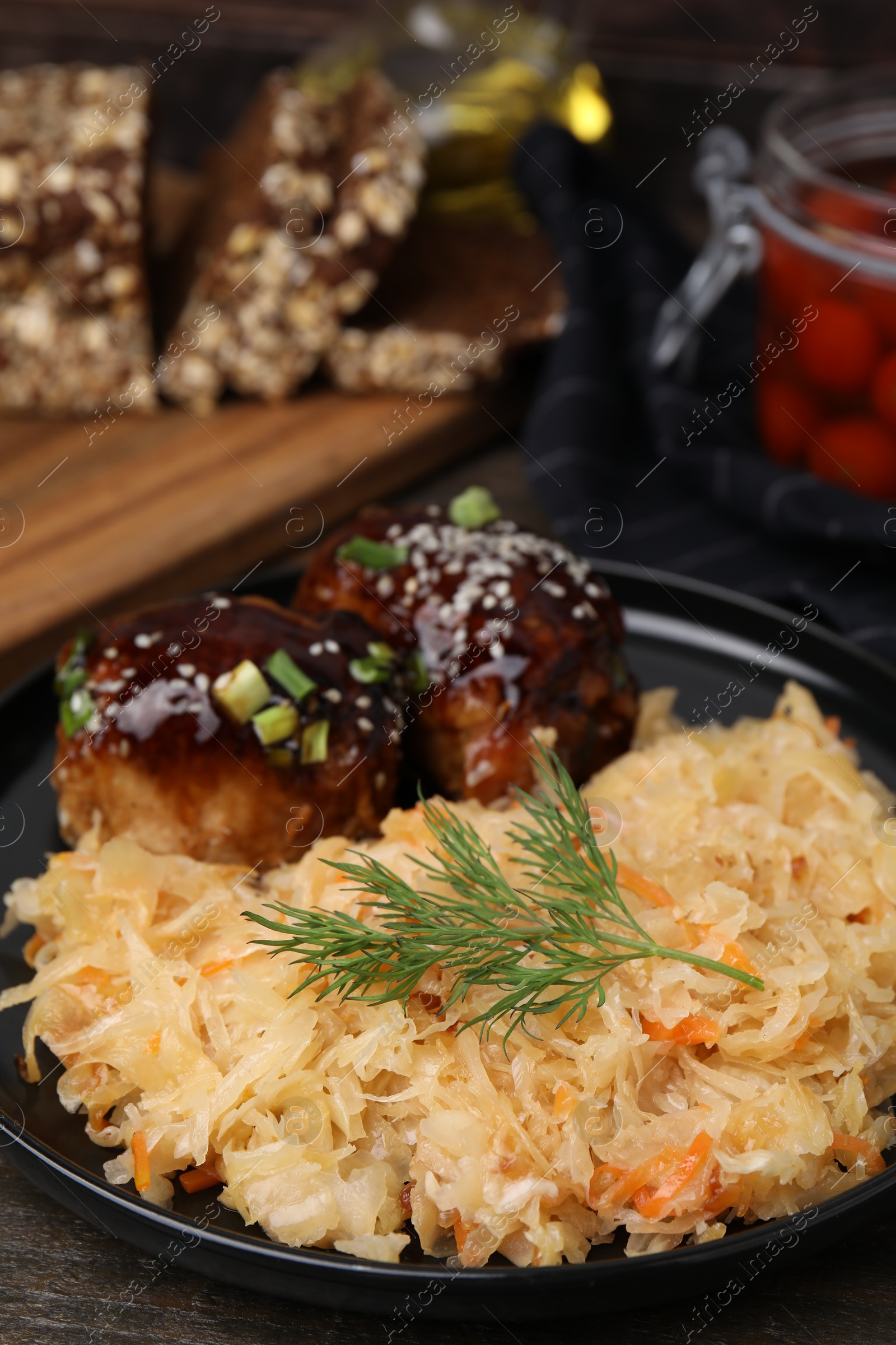 Photo of Plate with sauerkraut and chicken on wooden table, closeup