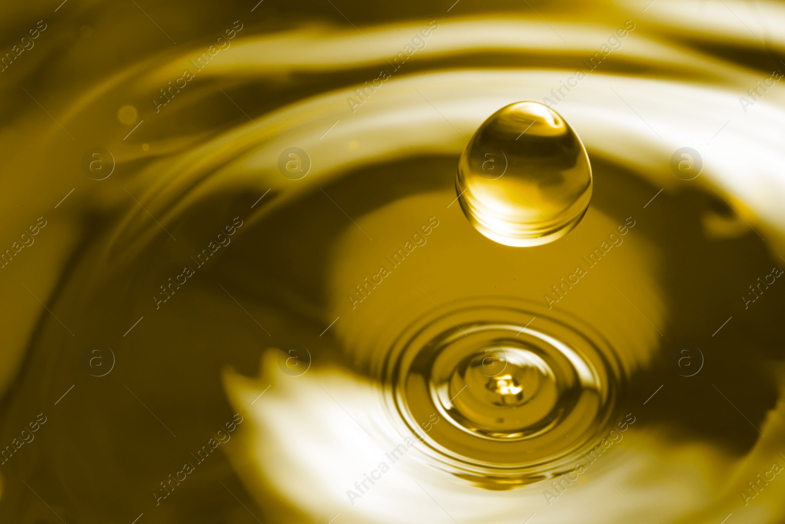 Image of Splash of golden oily liquid with drop as background, closeup. Space for text