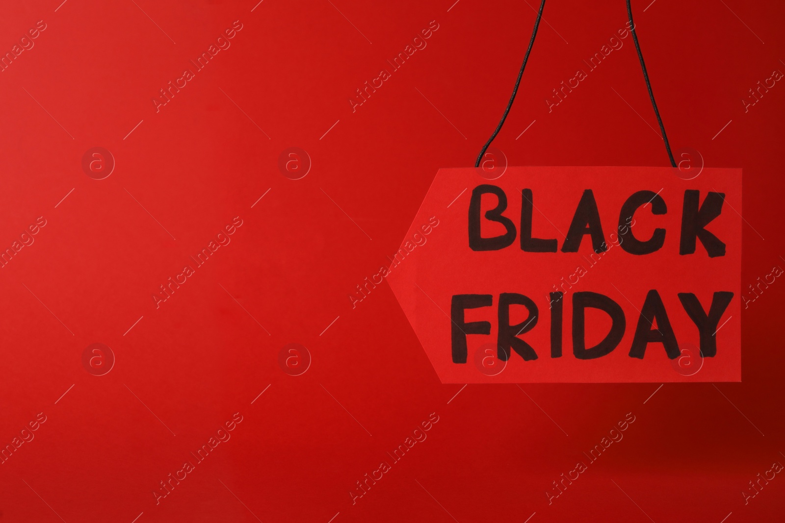 Photo of Tag with phrase Black Friday on red background. Space for text