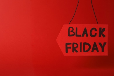 Photo of Tag with phrase Black Friday on red background. Space for text