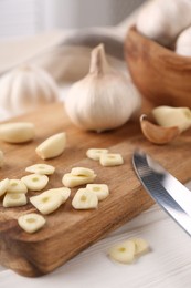 Photo of Aromatic cut garlic, cloves and bulbs on white wooden table, closeup