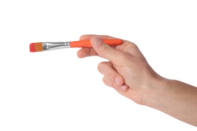 Photo of Young man holding brush with color paint on white background, closeup