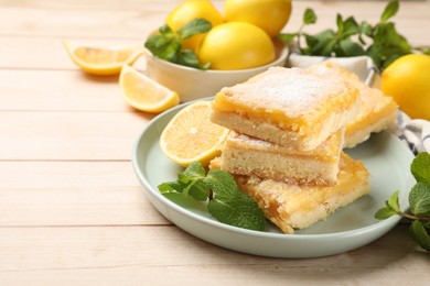 Photo of Tasty lemon bars with powdered sugar and mint on wooden table, closeup. Space for text