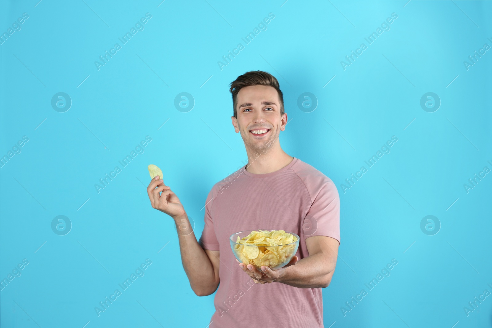 Photo of Man with bowl of potato chips on color background