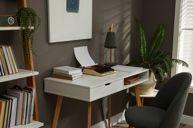 Photo of Comfortable writer's workplace interior with typewriter on desk near grey wall