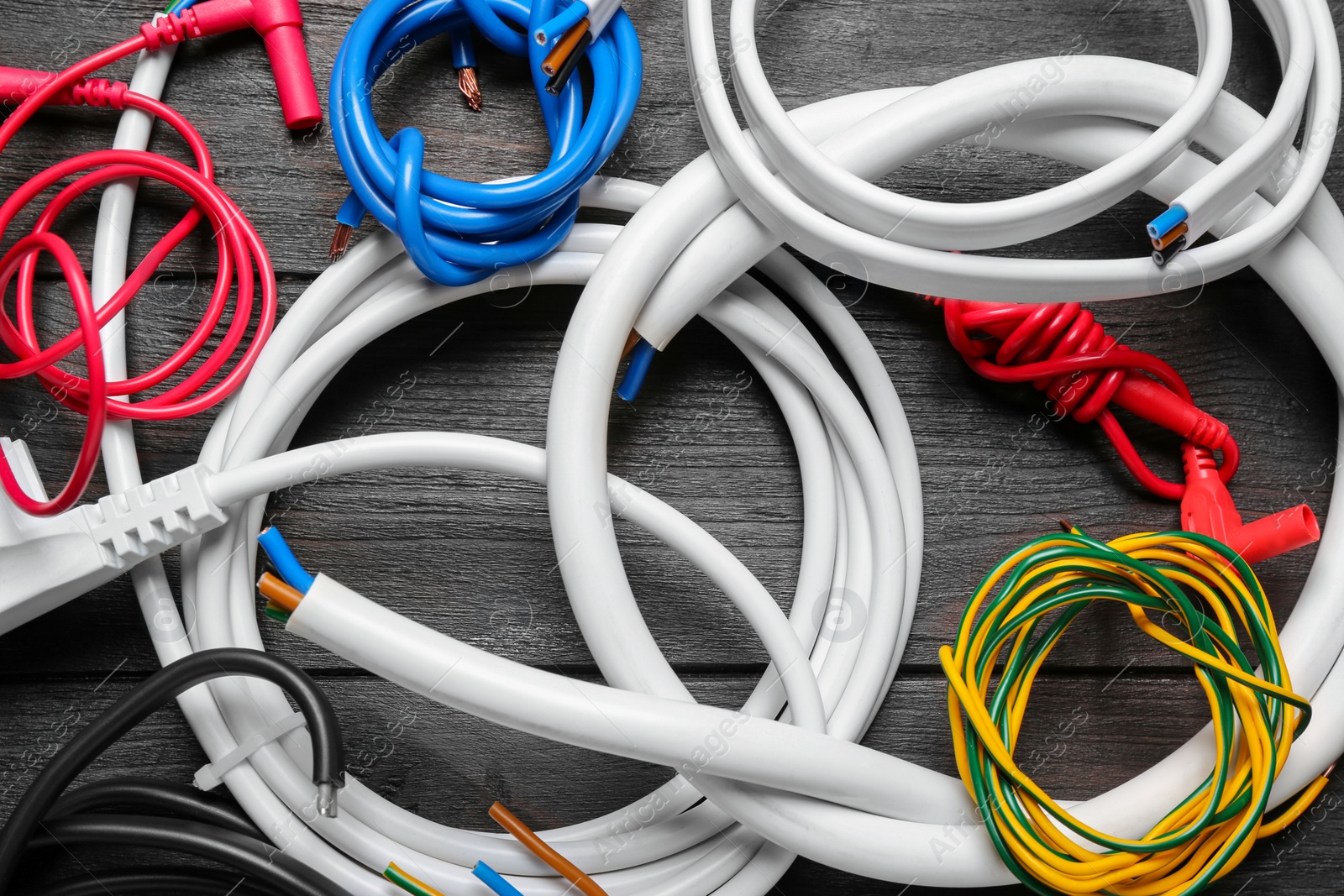 Photo of Different new electrical wires on wooden table, flat lay