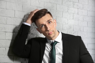 Photo of Portrait of young man with beautiful hair on brick wall background