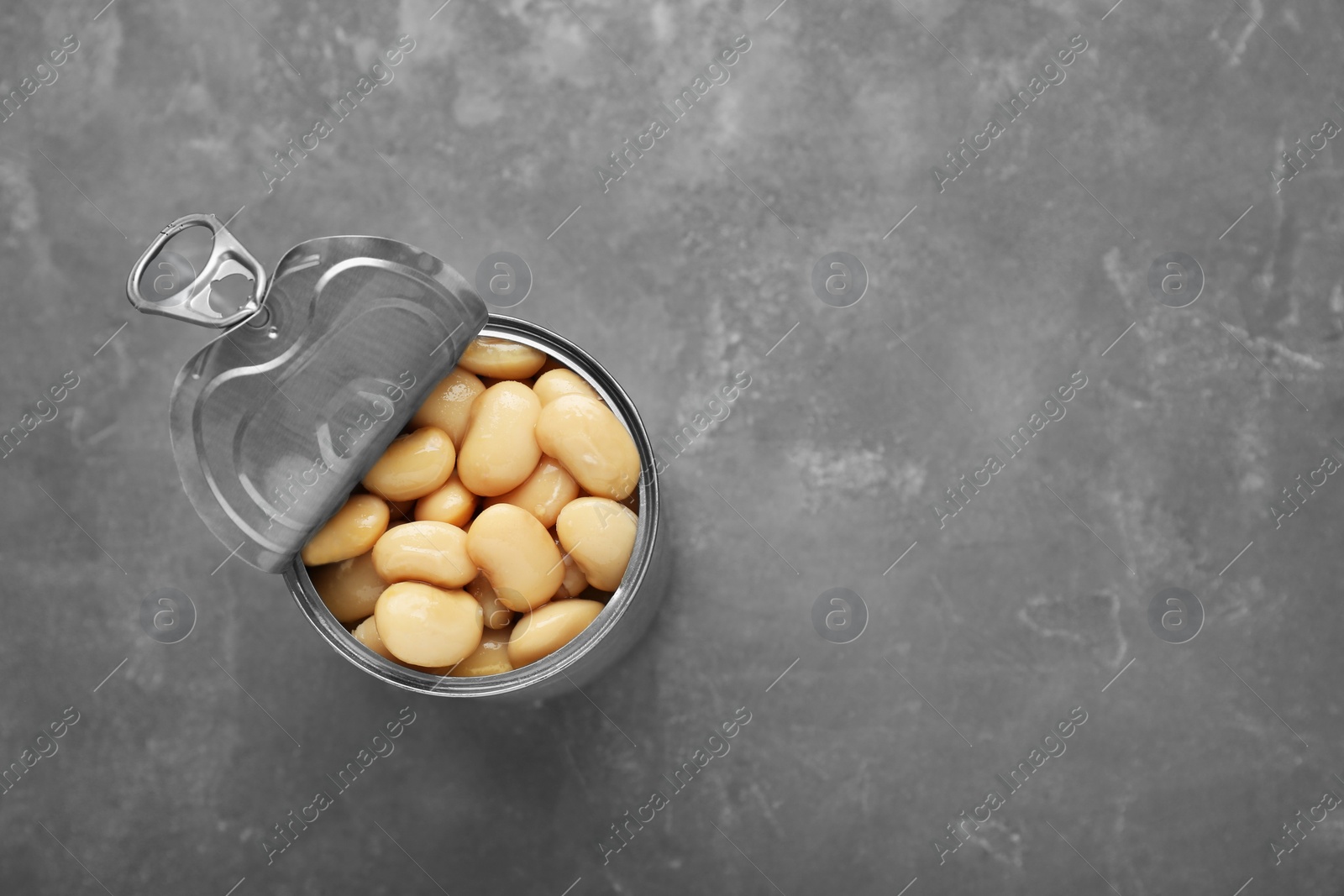 Photo of Tin can of canned white kidney beans on grey table, top view. Space for text