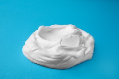 Photo of Sample of shaving foam on blue background, closeup