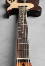 Photo of Modern electric guitar on color background, neck with strings in focus