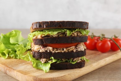 Delicious sandwich with tuna, tomatoes and lettuce on wooden table
