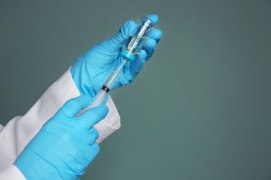 Doctor with syringe and medicine for vaccination on color background