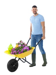 Male gardener with wheelbarrow and plants on white background