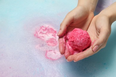 Photo of Woman holding bath bomb over water with foam, closeup. Space for text