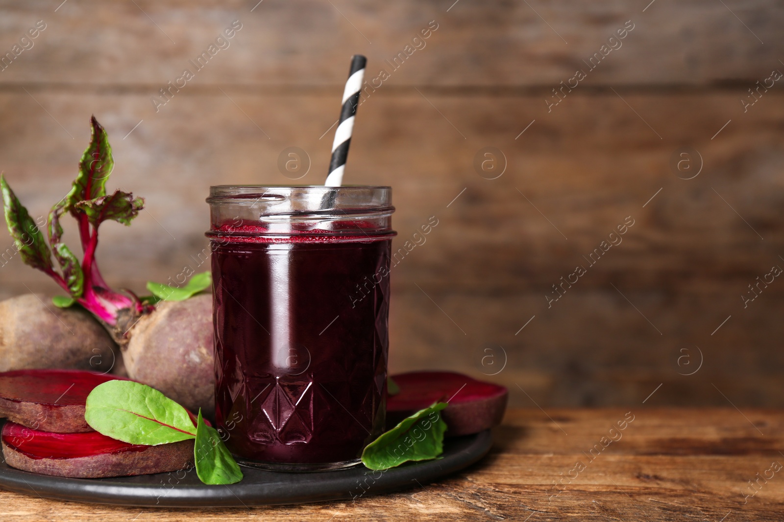 Photo of Freshly made beet juice on wooden table. Space for text