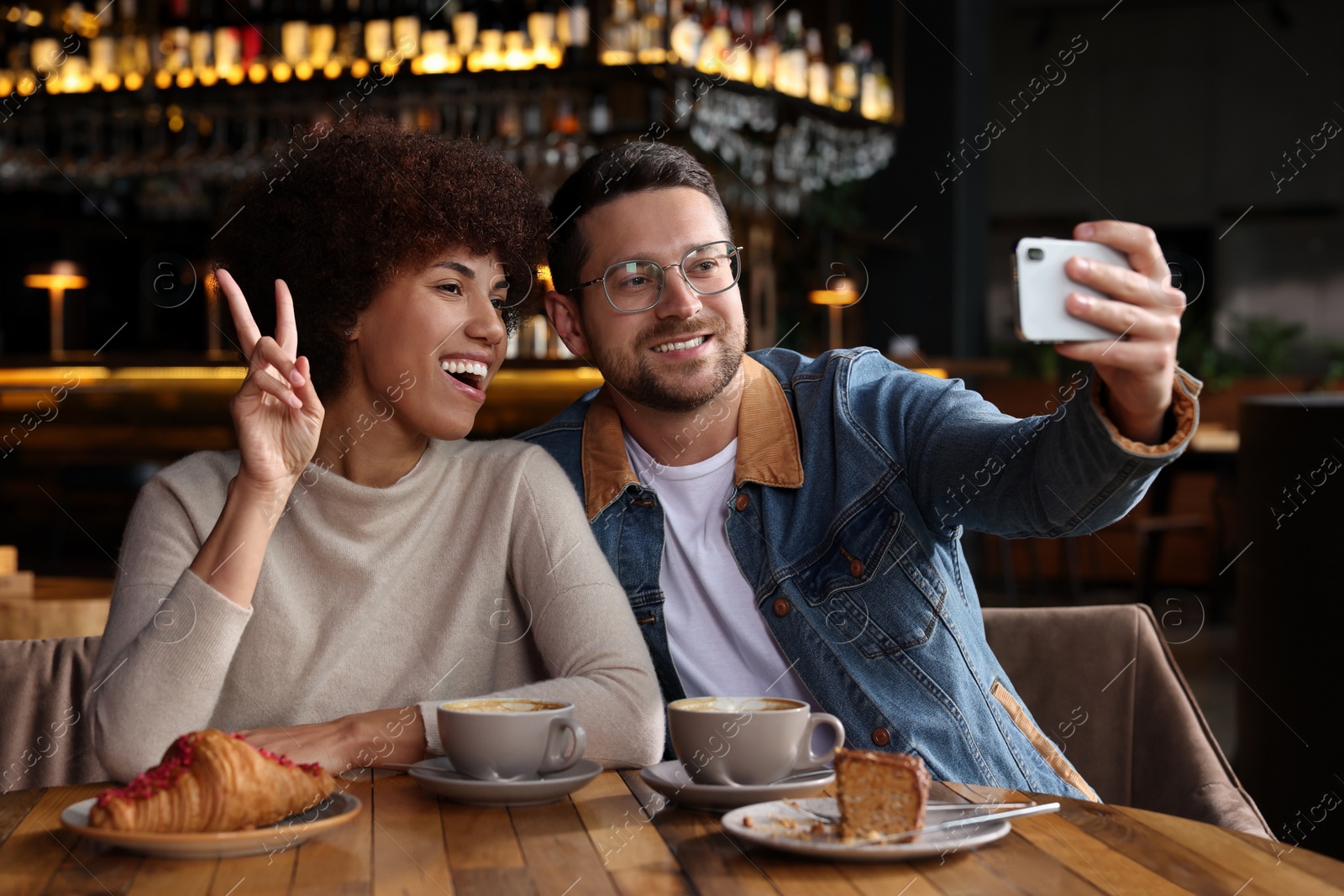 Photo of International dating. Happy couple taking selfie in cafe