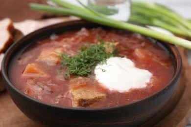 Tasty borscht with sour cream in bowl on table, closeup