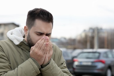 Photo of Sick man coughing outdoors, space for text. Cold symptoms